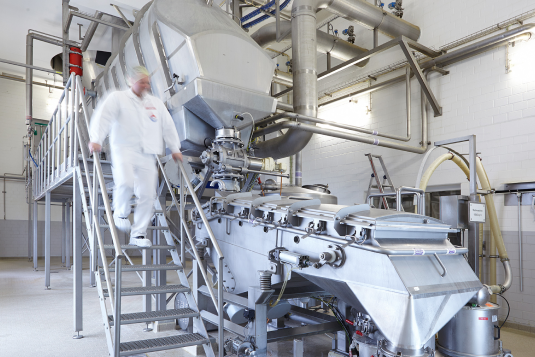 Ein Mitarbeiter von Dr. Suwelack läuft die Treppe von einem Produktionsgerät der Fabrik runter.