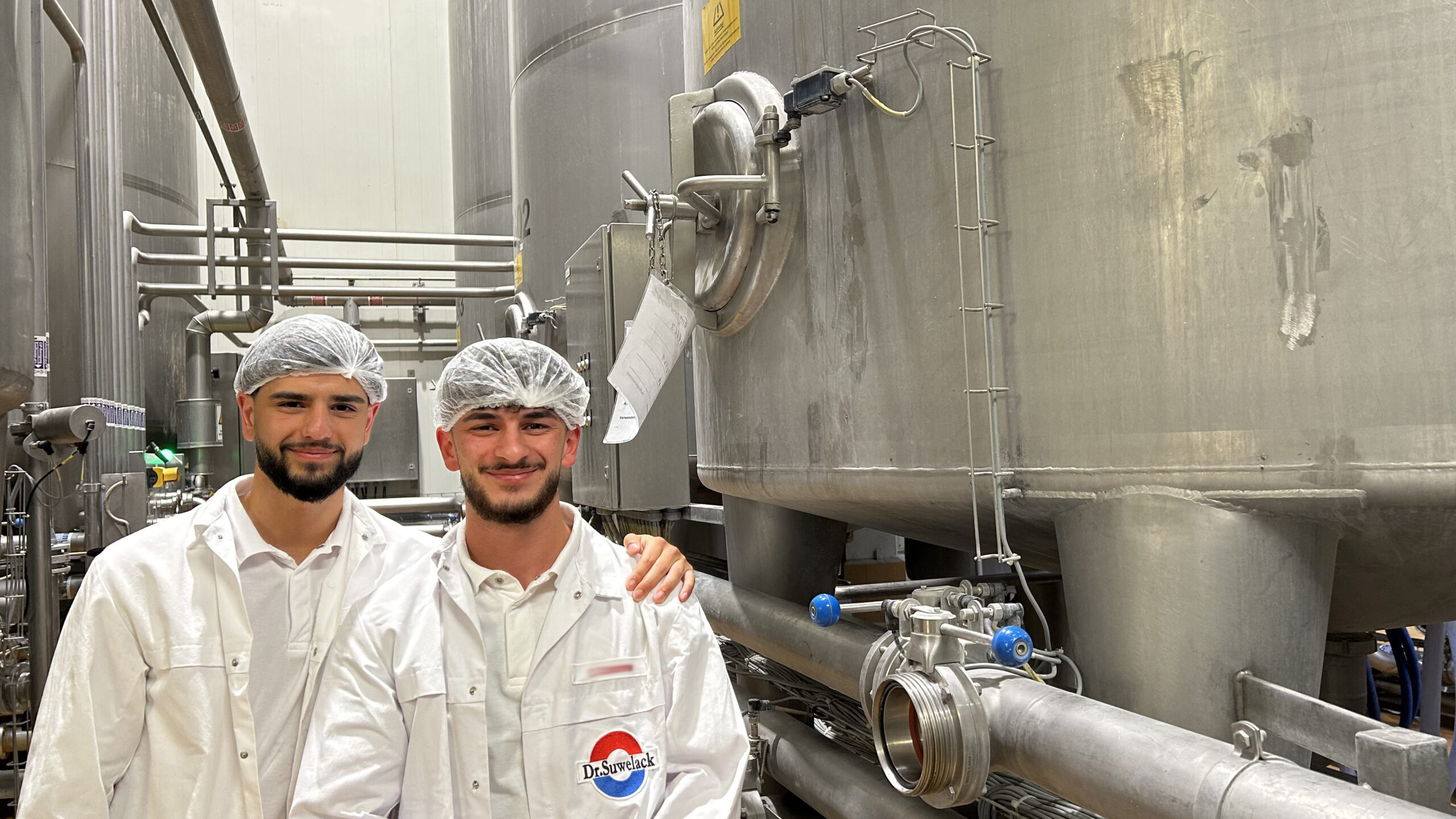 Die Auszubildenden Kadir und Can vor Produktionsmaschienen bei Dr. Suwelack.